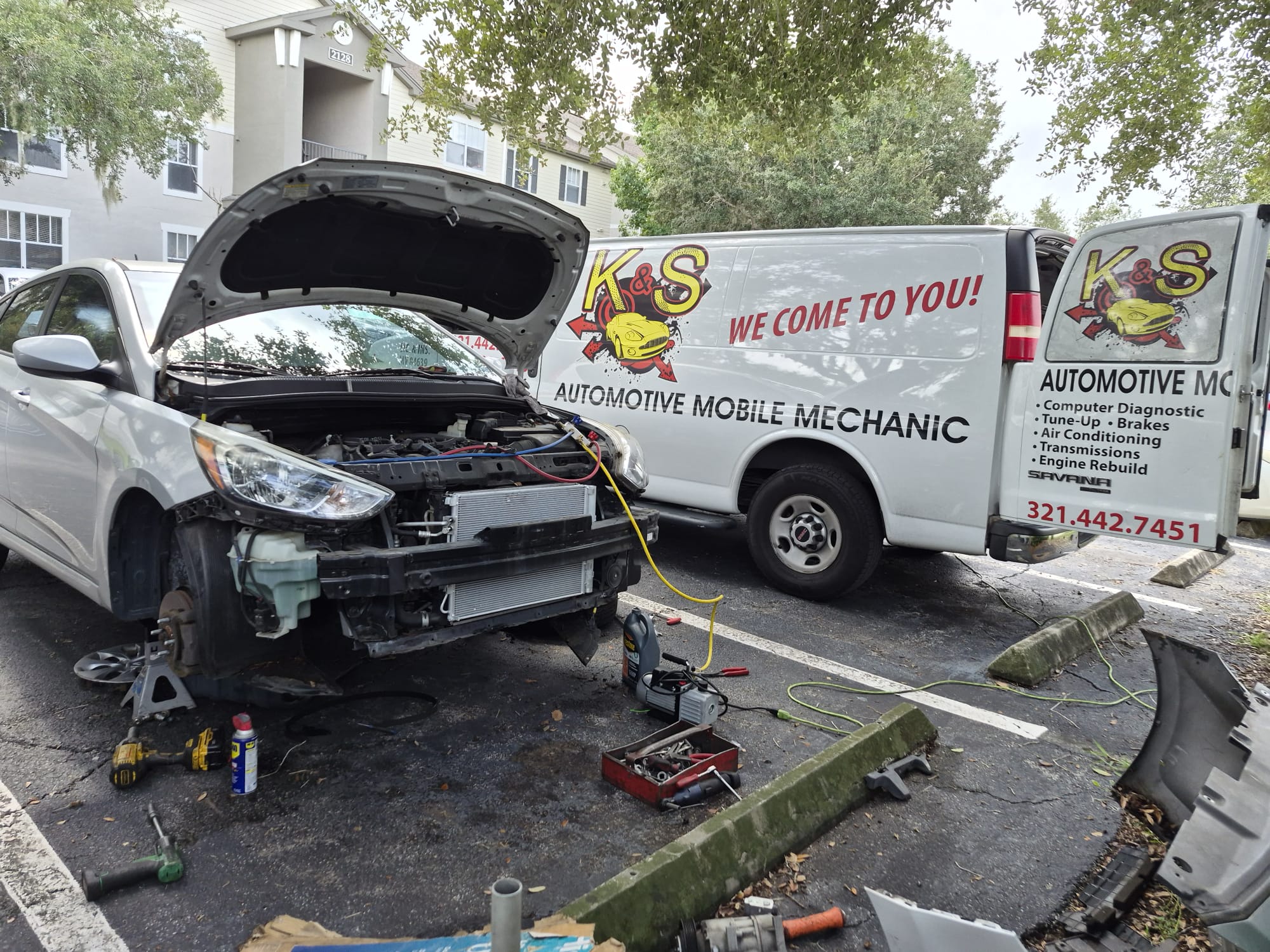 K&S van parked next to a car with the front bumper off for cooling system work