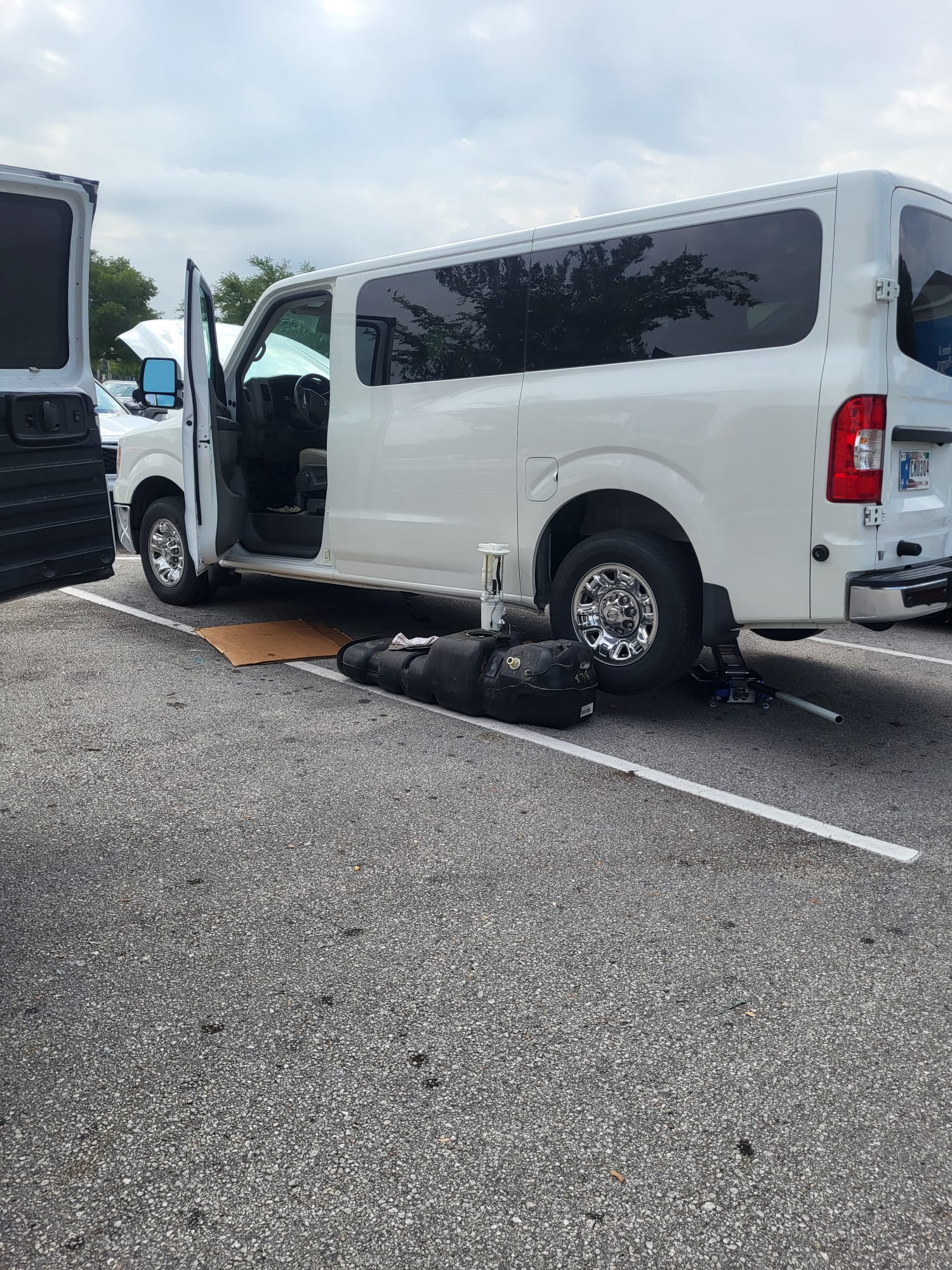 A van with the rear wheel off, jacked up for brake work in a parking lot