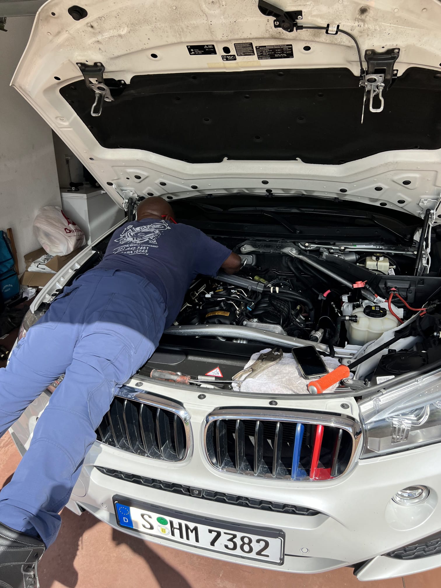 Kirk working under the hood of a white BMW