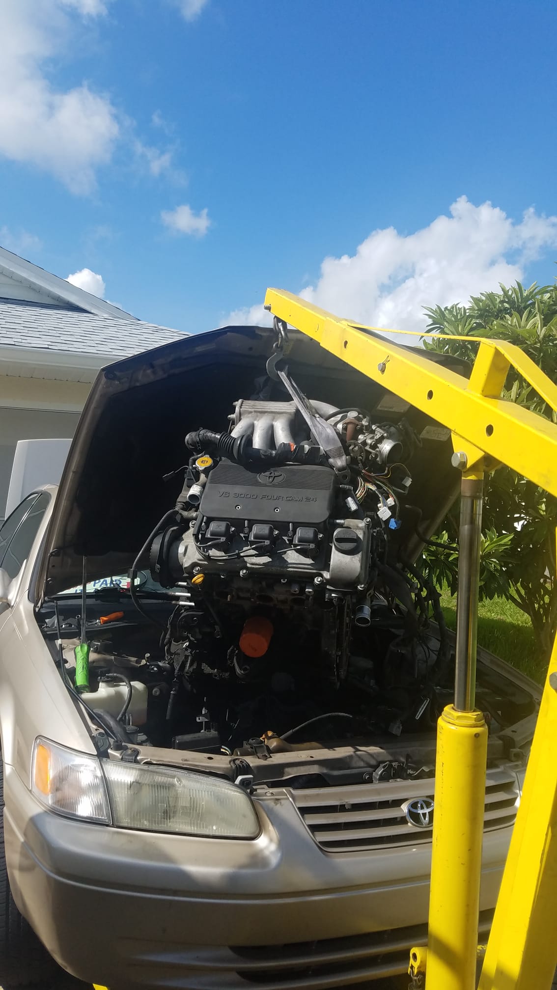 A Toyota with the engine lifted partway out by a hoist